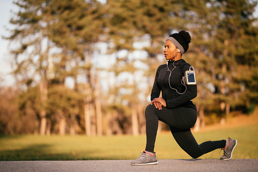 African American female athlete doing stretching exercises while warming up in nature. Copy space.