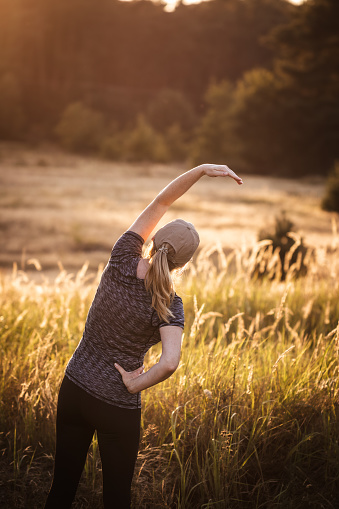 Woman is doing cardiovascular exercise outdoors during sunset. Fitness active lifestyle