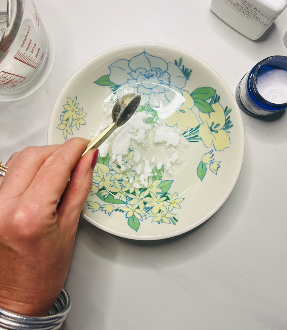 Bowl with water and a hand adding hyaluronic acid powder.